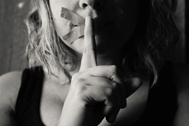 woman holding finger to her lips.